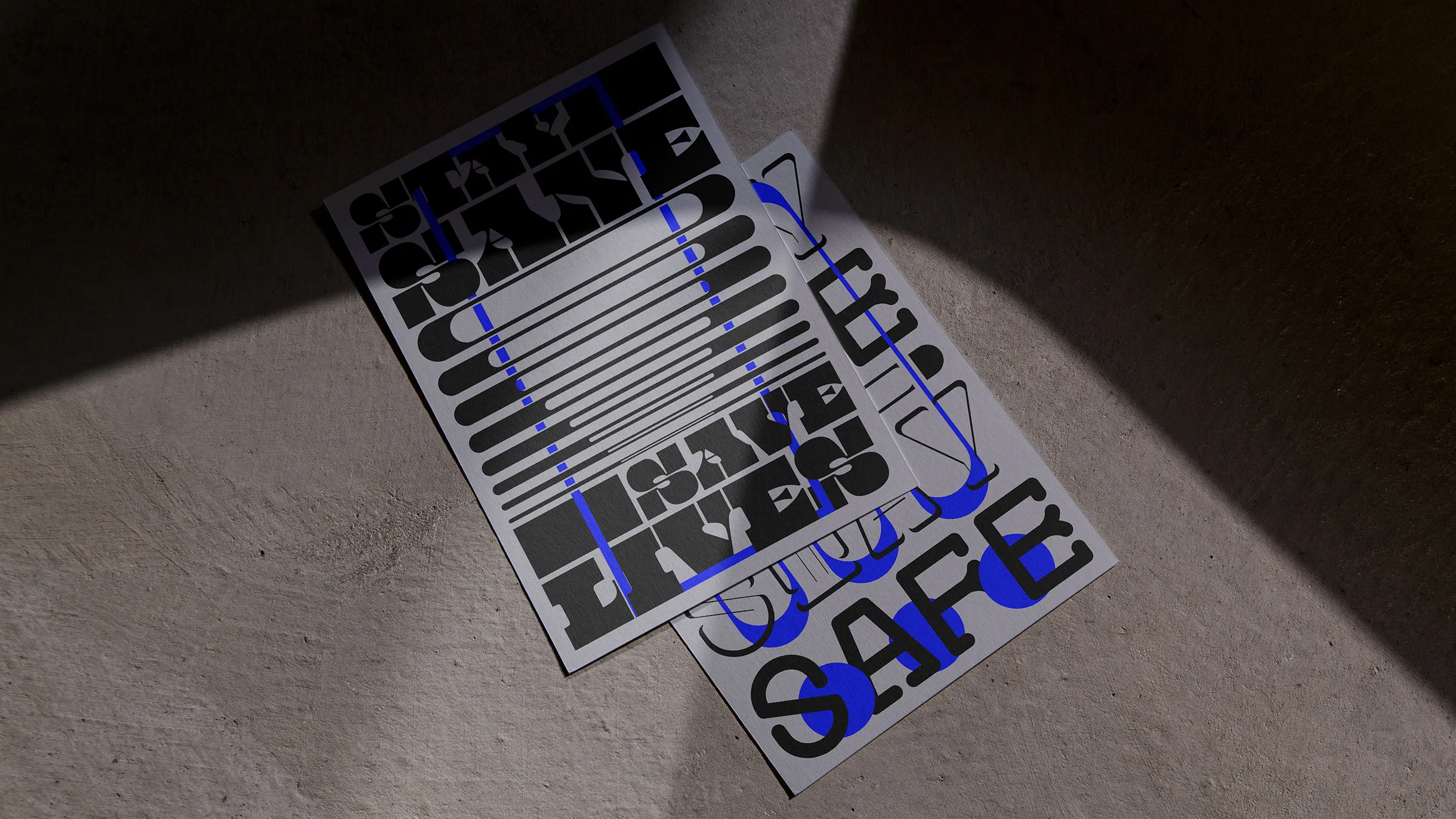 Two postcards with abstract black and blue typography placed on a textured surface with diagonal shadow.
